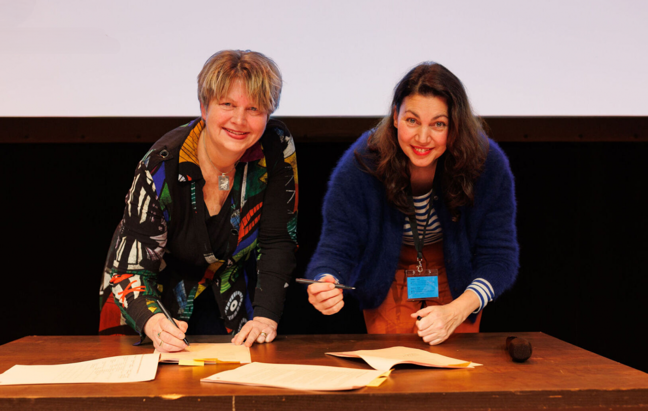 Marieke Vegt (Voorzitter Raad van Twaalf en directeur-bestuurder stichting Kunst & Cultuur) en Gabbi Mesters (directeur-bestuurder Fonds voor Cultuurparticipatie) ondertekenen de samenwerkingsovereenkomst. Fotograaf: Rutger Vos